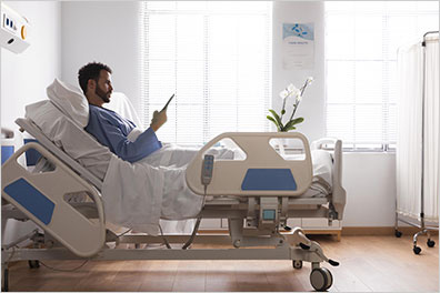 patient dans un lit d'hôpital tenant une tablette